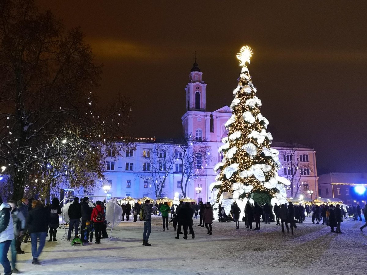 A Christmas market lit up at night with a giant decorated tree