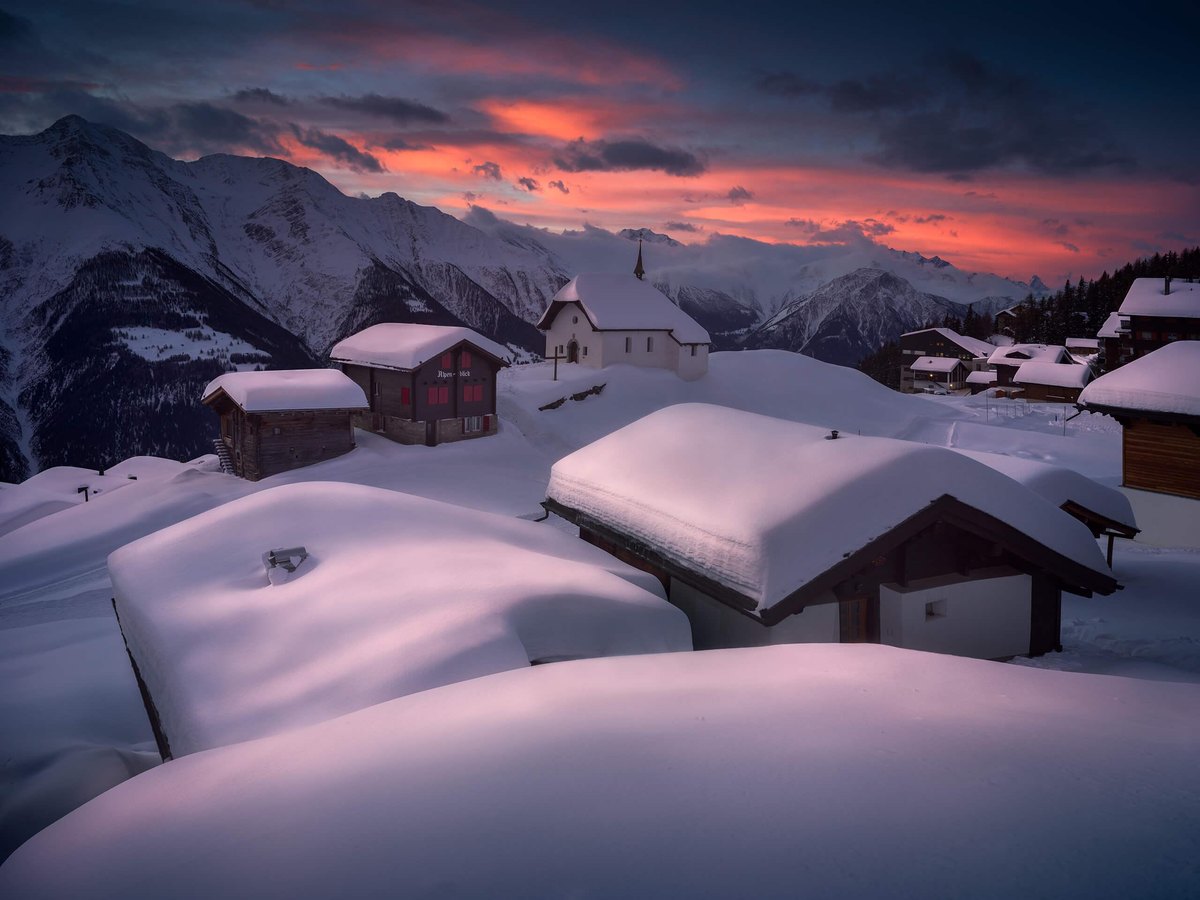 A snow-covered alpine village at sunset in the Swiss mountains