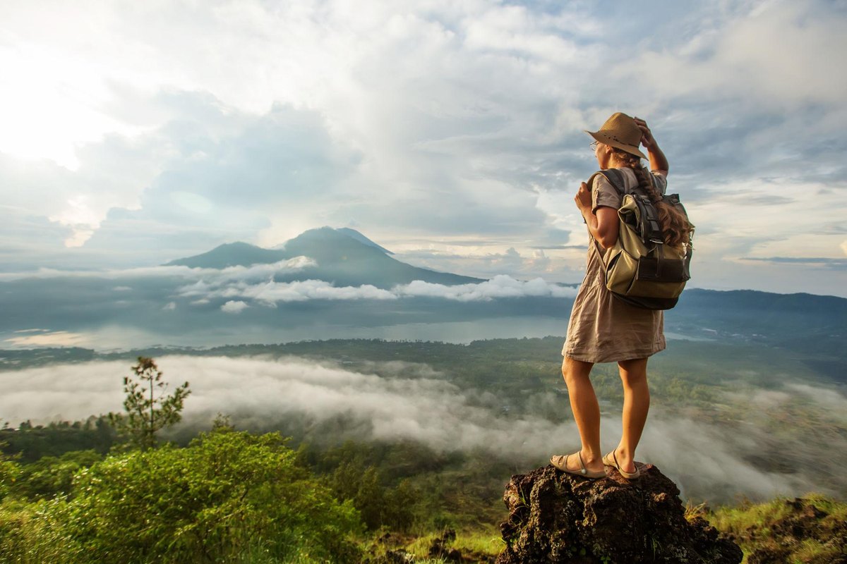 A solo traveler with a backpack looking out over a scenic viewpoint