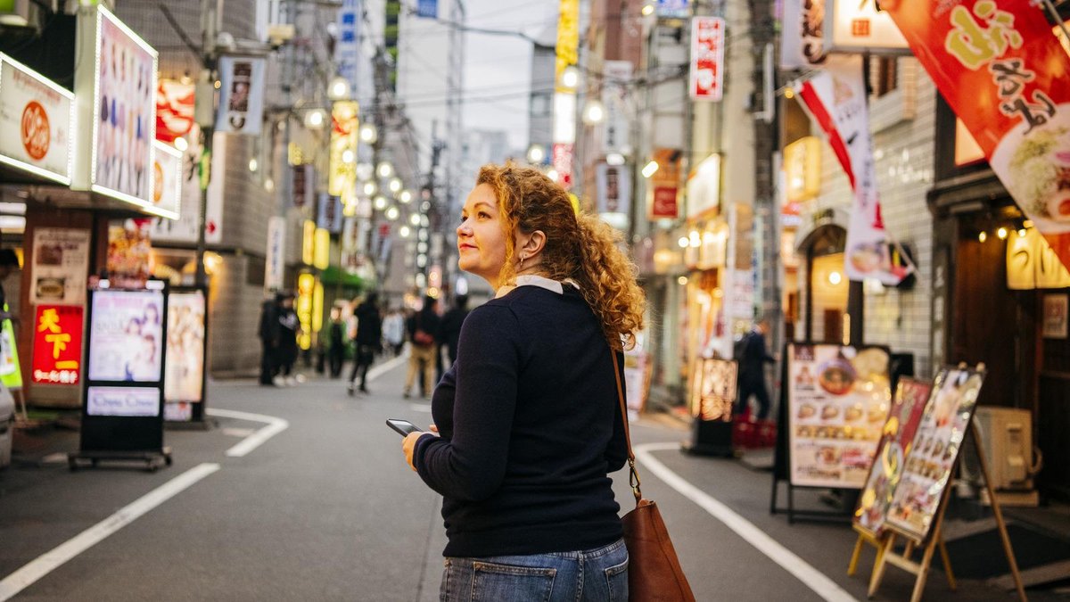 A solo traveler on a neon-lit Tokyo street in the evening