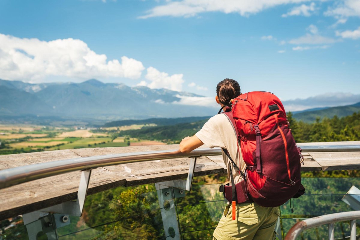 A backpacker at a mountain viewpoint over a green valley