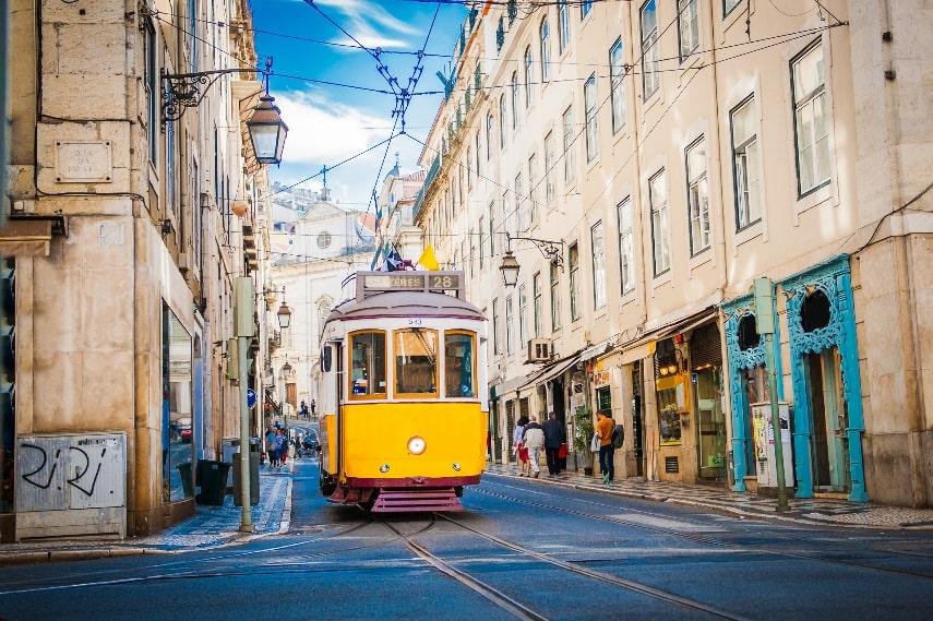 Lisbon's iconic yellow Tram 28 on a narrow city street