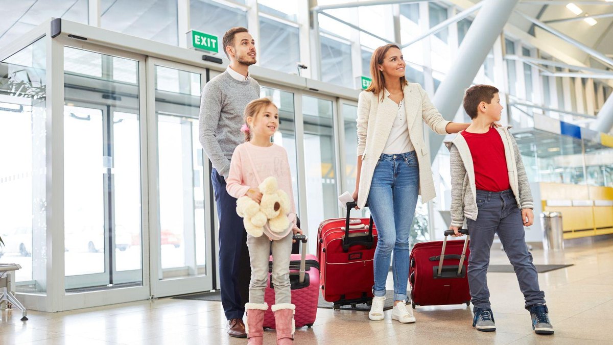 A family with suitcases walking through an airport terminal