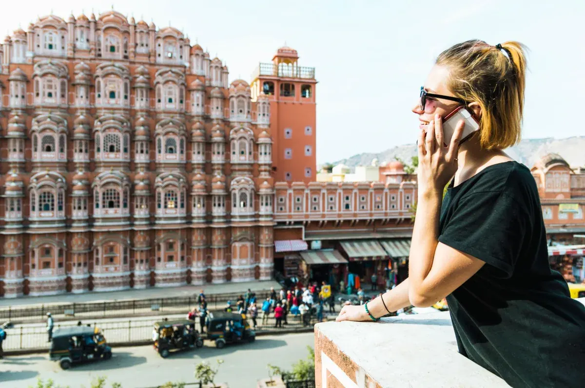 A traveler on her phone in front of Hawa Mahal, Jaipur