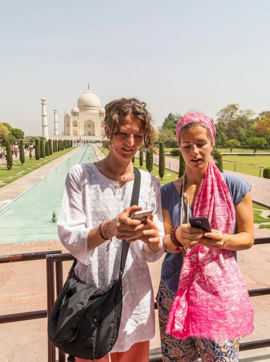 Travelers using their phones at the Taj Mahal in India
