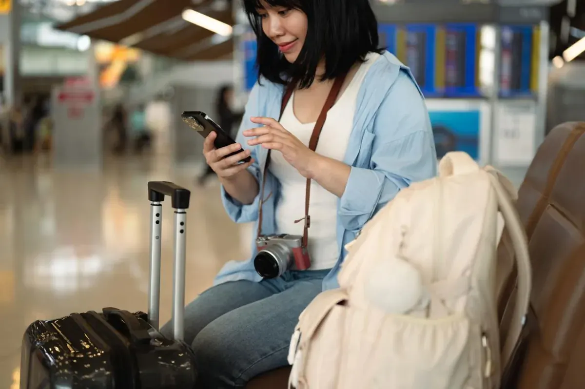 A traveler checking their phone in an airport terminal